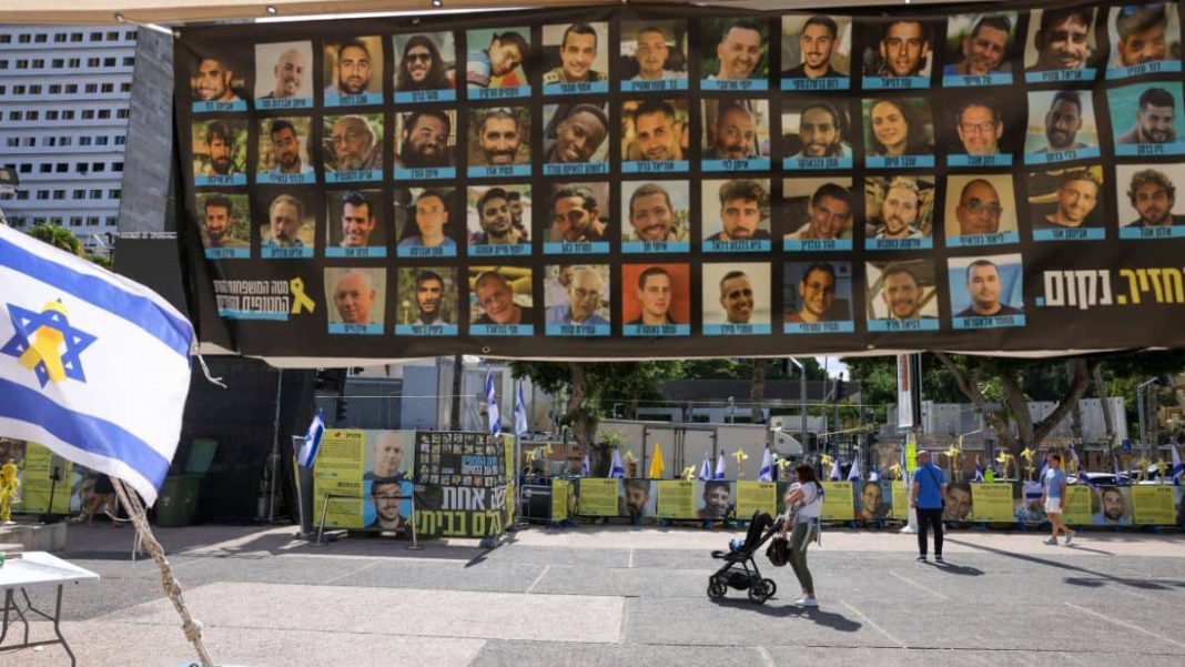People walk past posters of hostages held by the Palestinian militant group Hamas in Gaza at Hostage Square in Tel Aviv on October 10, 2025. AFP