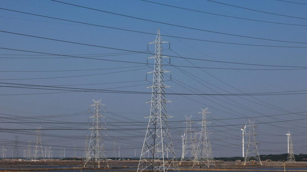 A view shows high-tension electricity power line pylons and power generating windmill turbines on Ahmedabad-Bhuj national highway. Image for representation only. File | Photo Credit: Reuters