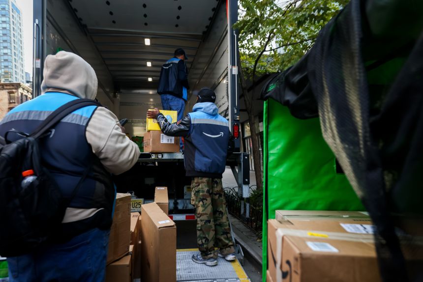 Workers unload Amazon packages from a Prime delivery truck in New York on October 28, 2025.