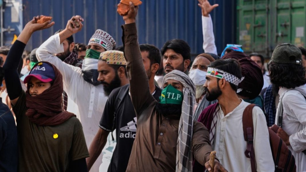 Supporters of Islamist party 'Tehreek-e-Labbaik Pakistan' chant religious slogans near their party's headquarters on a road barricaded with shipping containers by police to stop their pro-Palestinian march toward capital Islamabad, in Lahore, Pakistan, Friday, Oct. 10, 2025. (AP Photo)