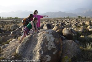 Archaeologists and divers are pictured at the site, surrounded by the dramatic Tianshan mountains