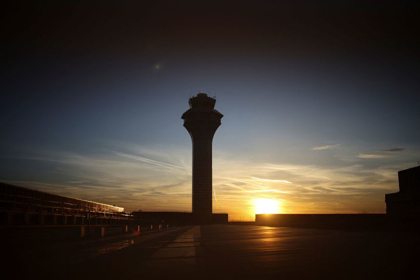 The sun sets over an air traffic control tower at O'Hare International Airport in Chicago. A shortage of air traffic controllers has become worse due to resignations and retirements during the recent government shutdown.