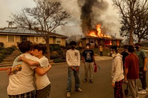 Residents embrace outside a burning property as the Eaton Fire swept through in Altadena, Calif., on Jan. 8. Ethan Swope / AP file