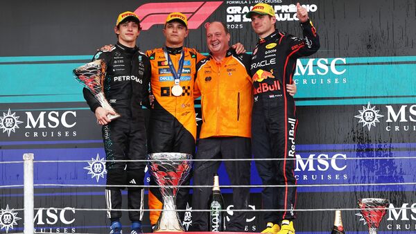 McLaren's Lando Norris celebrates on the podium with a trophy after winning the Sao Paulo Grand Prix with second placed Mercedes' Andrea Kimi Antonelli and third placed Red Bull's Max Verstappen