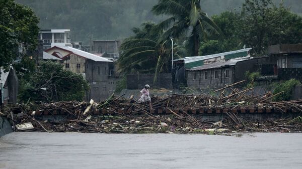 A man walks past debris along the shores of a river at Polangui in Albay province, south of Manila on November 9, 2025, after Super Typhoon Fung-wong made landfall. Super Typhoon Fung-wong slammed into the Philippines' eastern seaboard on November 9, the national weather service said, after killing at least two people and forcing more than a million to evacuate.