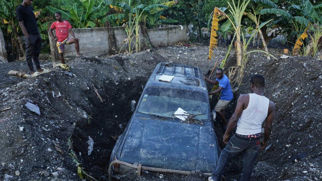 Residents work to remove a partially buried vehicle in the aftermath of Hurricane Melissa in Petit-Goave, Haiti, on November 6, 2025. | Photo Credit: AP