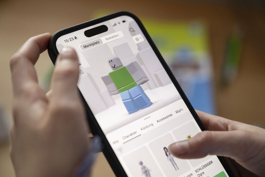 A girl uses Roblox on a smartphone. Roblox is making new efforts to verify users' ages to protect children.