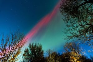 Pink and green streaks caused by energized particles from the sun interacting with gases in Earth's atmosphere can be seen over Minneapolis, Minnesota, on Tuesday.