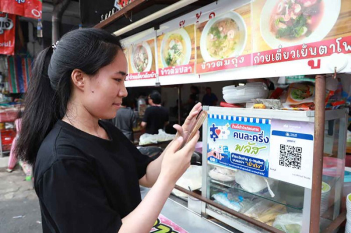 A woman her phone to scan a QR code to make a purchase at a noodle shop under the government's co-payment plus scheme. (File photo)