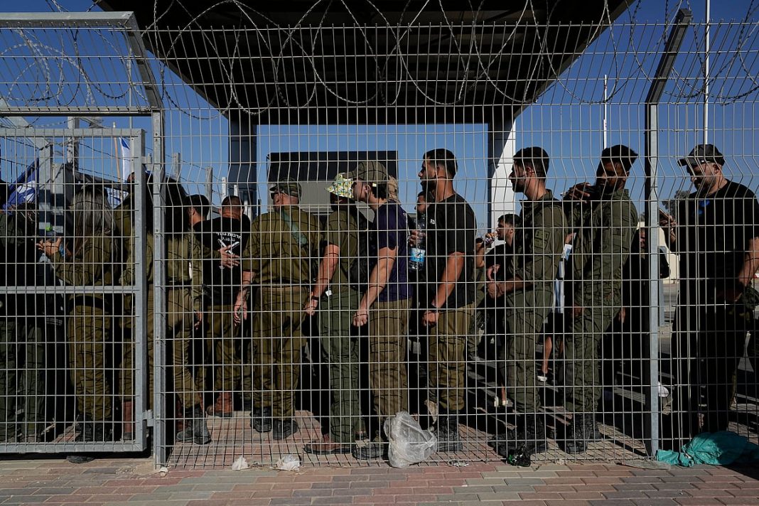 Israeli soldiers gather at the gate to the Sde Teiman military base, as people protest in support of soldiers being questioned for detainee abuse, July 29, 2024.