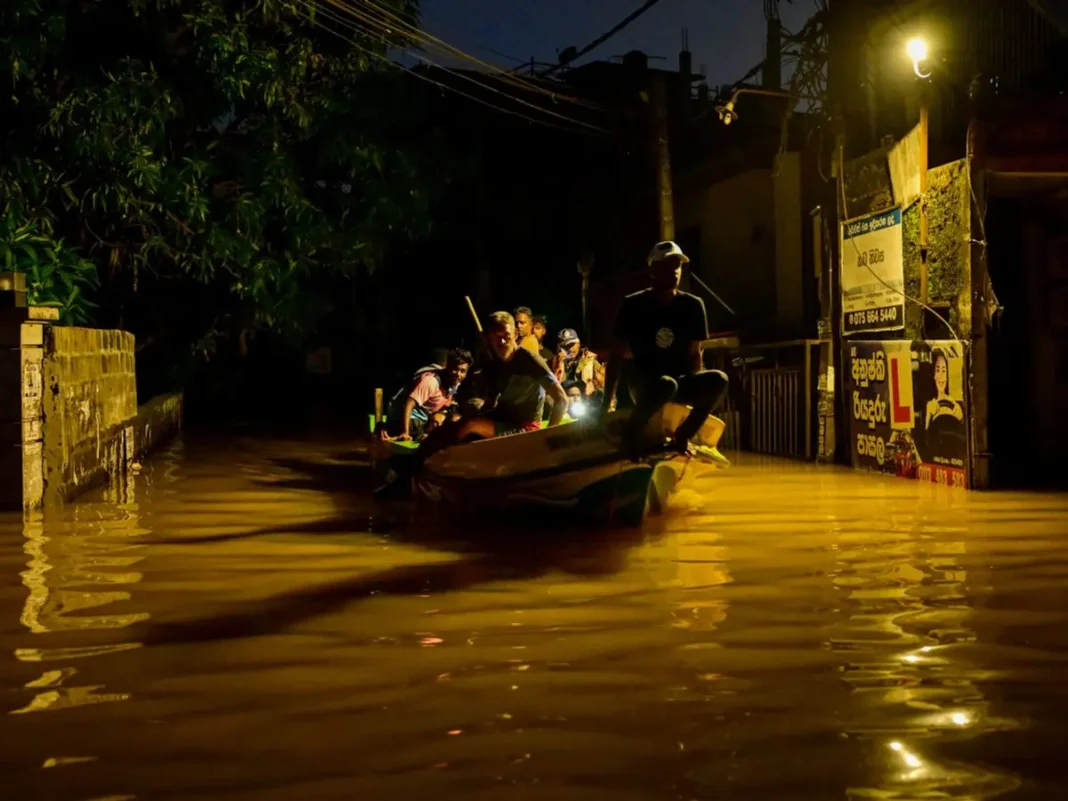 People ride on a boat belonging to Sri Lanka's army at a flooded street after heavy rainfall in Wellampitiya on the outskirts of Colombo on November 30, 2025.