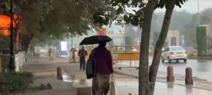 A woman walks with an umbrella amid rain in Delhi. (Photo: Screengrab)