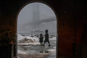 Pedestrians walk on a street as snow falls during a winter storm in New York City. (Photo: Reuters)