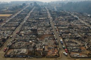 Cars line the streets near wildfire-burned homes in Tome, Chile. (Photo: AP)
