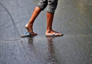 A man struggles to cross a road after his slippers got stuck in melted tar on a hot day. (Photo: Reuters)