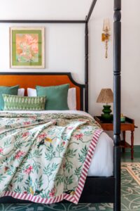 A classic black four-poster bed frame provides a sharp silhouette against the white walls of the bedroom.