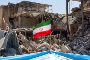 An Iranian flag is placed amids rubble and debris next to a destroyed residential building near Ferdowsi square in Tehran on March 3, 2026. (AFP)