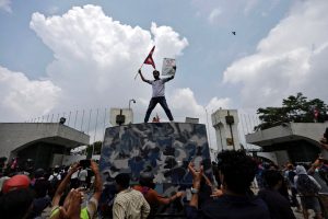 A demonstrator holding a placard waves Nepal's national flag as he stands atop a water cannon vehicle belonging to the Armed Police Force (APF) outside the entrance of Parliament during youth-led protests that toppled Nepal's prime minister, in Kathmandu, on September 8, 2025. (Reuters File Photo)