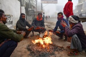 People warm themselves around a small fire during a cold and foggy winter morning. (Photo: PTI)