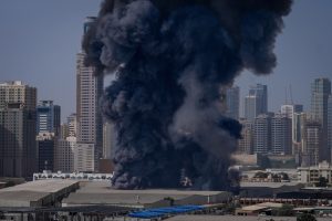 FILE - A black plume of smoke rises from a warehouse in the industrial area of Sharjah City following reports of Iranian strikes in Dubai, United Arab Emirates, on March 1, 2026. (AP Photo/Altaf Qadri, File)