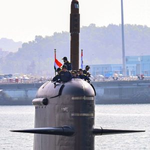 Indian Navy crew members stand atop the conning tower of a Kalvari-class submarine as it returns to harbour, flying the national flag. (Photo: PTI)