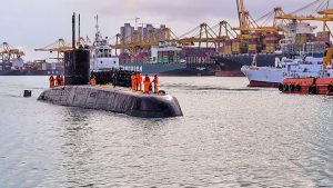 A Kalvari-class Indian Navy submarine arrives at port, with crew members in orange safety gear lining its deck. (Photo: PTI)