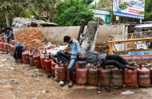 People wait with empty LPG cooking gas cylinders to avail refilled ones, in Prayagraj. (Photo: PTI)