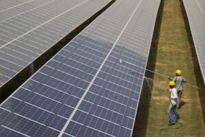 Workers clean photovoltaic panels inside a solar power plant in Gujarat. (Photo: Reuters)