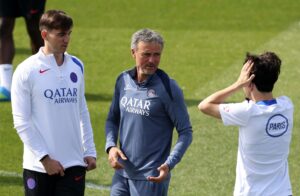 PSG head coach Luis Enrique (C) speaks with Vitinha (R) and Fabian Ruiz during a training session.