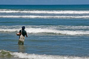 A man fishing in ocean waves. (Photo: Pexels)