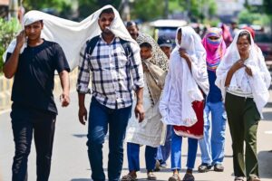 People walk while shielding themselves from the heat in Prayagraj. (Photo: PTI)