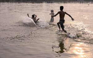Young boys beat the heat by playing in a waterbody in West Bengal. (Photo: PTI)
