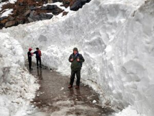 People walk along a snow-cleared path amid heavy accumulation following fresh snowfall near Kedarnath Dham. (Photo: PTI)