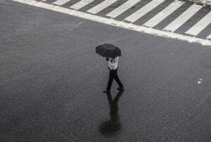 A traffic police official walks across a road during rain, in Gurugram, Haryana. (Photo: PTI)