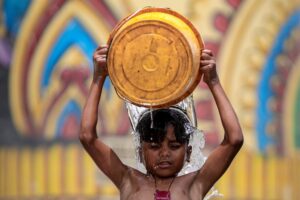 A boy pours a bucket of water to beat the heat on a hot summer day in UP. (Photo: PTI)