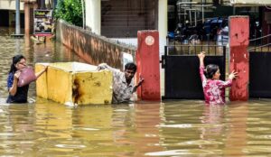 People wade through a waterlogged area after heavy rainfall, in Guwahati, Assam. (Photo: PTI)