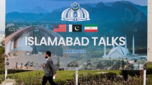 A man walks past a billboard near the media centre as delegations from the United States and Iran are expected to hold peace talks in Islamabad. (Photo: Reuters)