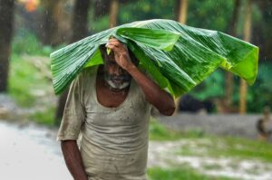 A man covers himself amid heavy rainfall, in Morigaon district, Assam. (Photo: PTI)